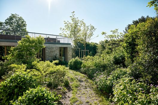 Üppig bepflanzter Privatgarten mit Natursteinfassade, Kiesweg und Staudenpflanzungen