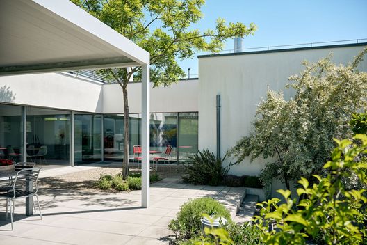 Bepflanzter Hanggarten mit Treppe, Feuerring und Sitzplatz vor modernem Wohnhaus