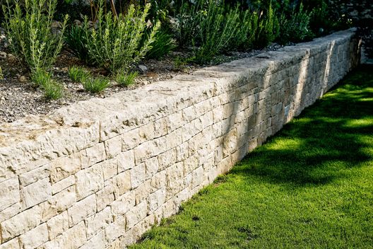 Kalksteinmauer mit Staudenbeet und Rasenfläche im hochwertig gestalteten Privatgarten