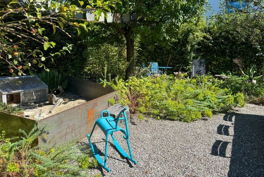 Naturnaher Garten mit Kiesfläche, Cortenstahl-Beeteinfassung, schattigem Sitzplatz unter einem Baum und vielfältiger trockenheitsverträglicher Bepflanzung.