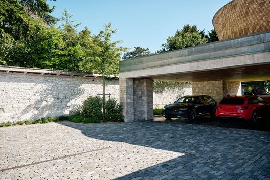 Garagenzufahrt mit Pflästerung aus Guber Naturstein und Carport bei hochwertigem Neubau