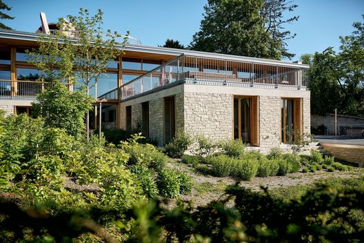 Moderner Neubau mit Natursteinfassade und vielfältiger Bepflanzung im Privatgarten