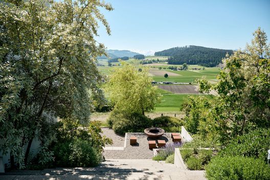 Treppenabgang durch den bepflanzten Hanggarten mit Feuerring und Aussicht auf die Landschaft